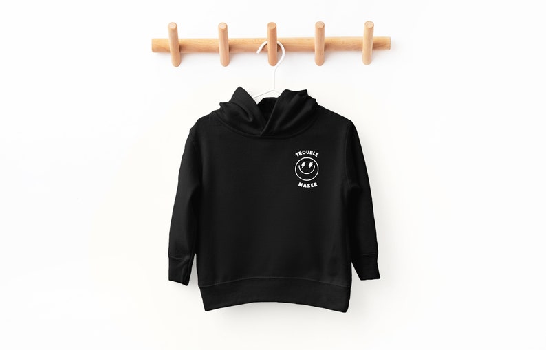 May include: Black hooded sweatshirt with a white smiley face graphic and the text "Trouble Maker" on the front.