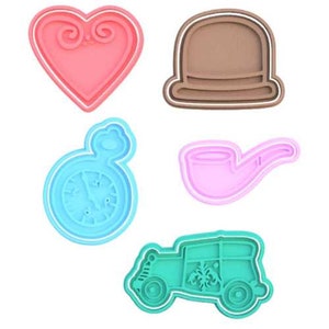 May include: Set of five cookie cutters in various shapes and colors. The cutters are shaped like a heart, a hat, a pocket watch, a pipe, and a car. The cutters are made of plastic and are designed for use with cookie dough.
