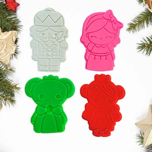 Peut inclure: Quatre emportes-pièces sur le thème de Noël : un casse-noisette gris, une fille rose, une souris verte et une fille rouge.