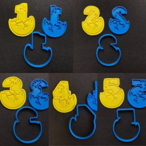 May include: A set of ten cookie cutters in the shape of numbers 1 through 5, with a dinosaur egg design. The cutters are made of blue and yellow plastic.
