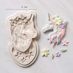 May include: Silicone mold for making unicorn cake toppers. The mold is 6.7 cm wide and features a unicorn head with a floral crown, a mane, and a horn. The mold also includes smaller molds for making flowers and leaves.
