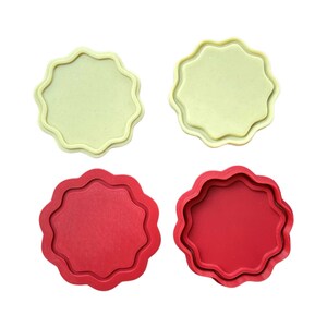 May include: Two sets of round, scalloped-edge cookie cutters. One set is yellow and the other is red.