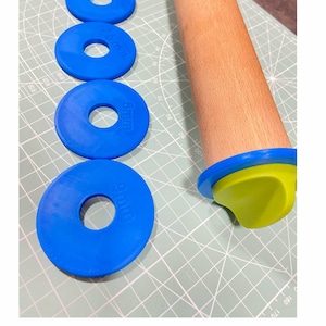 Puede incluir: Un conjunto de cinco cortadores de galletas de plástico azul y rojo de diferentes tamaños, con las palabras "SMALL", "MEDIUM" y "LARGE" impresas en ellos. También se ve un rodillo de madera con un mango verde y azul en la imagen.