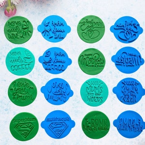 Op de afbeelding: Een set van 16 ronde koekjesvormen met verschillende ontwerpen en spreuken voor Moederdag. De vormen zijn blauw en groen en bevatten spreuken zoals "Mama heeft wijn nodig", "Gelukkige Moederdag" en "Goede moeders zeggen vervelende dingen".