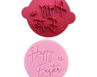 May include: Two round silicone stamps for baking and decorating. The top stamp is red and says "Happy Easter" in a cursive font. The bottom stamp is pink and says "Happy Easter" in a cursive font.