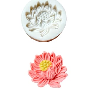 Puede incluir: Un molde de silicona blanco con forma de flor de loto rosa. El molde se utiliza para hacer decoraciones de pasteles o fondant.