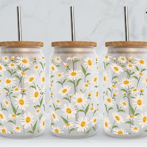 May include: Three clear glass tumblers with wooden lids and stainless steel straws. Each tumbler features a white daisy pattern on a white background.