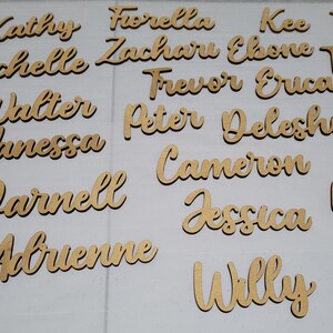 May include: A collection of individual wooden name cutouts in a cursive script font. The names include Kathy, Fiorella, Kee, Michelle, Zacharu, Ebone, Walter, Frevor, Erica, Vanessa, Peter, Deleshia, Cameron, Darnell, Jessica, Adrienne, and Willy.