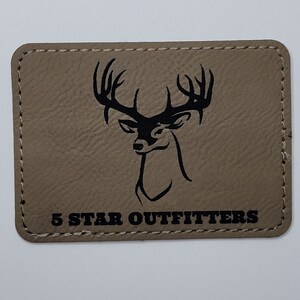 May include: A tan leather patch with a black silhouette of a deer head with antlers and the text "5 STAR OUTFITTERS" below.