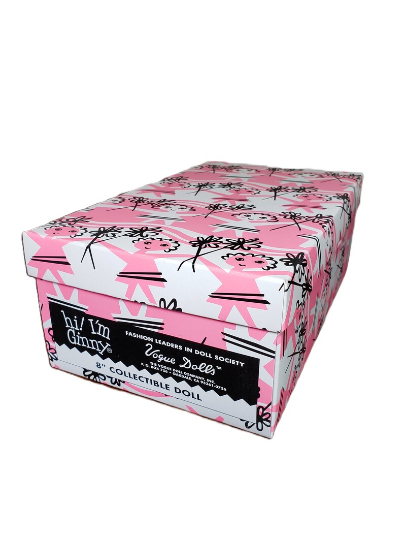 Pu&ograve; includere: Scatola rettangolare con motivo floreale rosa e bianco. La scatola presenta il testo "hi! I'm Ginny" e "Vogue Dolls". &Egrave; etichettata come bambola da collezione da 20 cm.