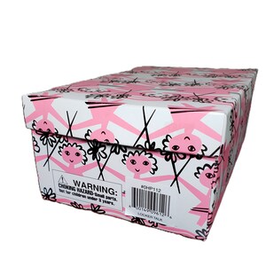Pu&ograve; includere: Una scatola rettangolare con sfondo bianco e un motivo ripetuto di figure rosa e accenti floreali neri. La scatola ha un'etichetta di avvertimento e un codice a barre con la scritta "LOCKER TALK".