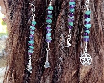 May include: Four silver hair charms with green and purple gemstone beads. Each charm features a different witchy symbol: a witch's hat, a broom, a pentagram, and a crescent moon.