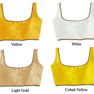 May include: Four different colored sleeveless tops with a scoop neck and a brown beaded trim. The colors are yellow, white, light gold, and cobalt yellow.