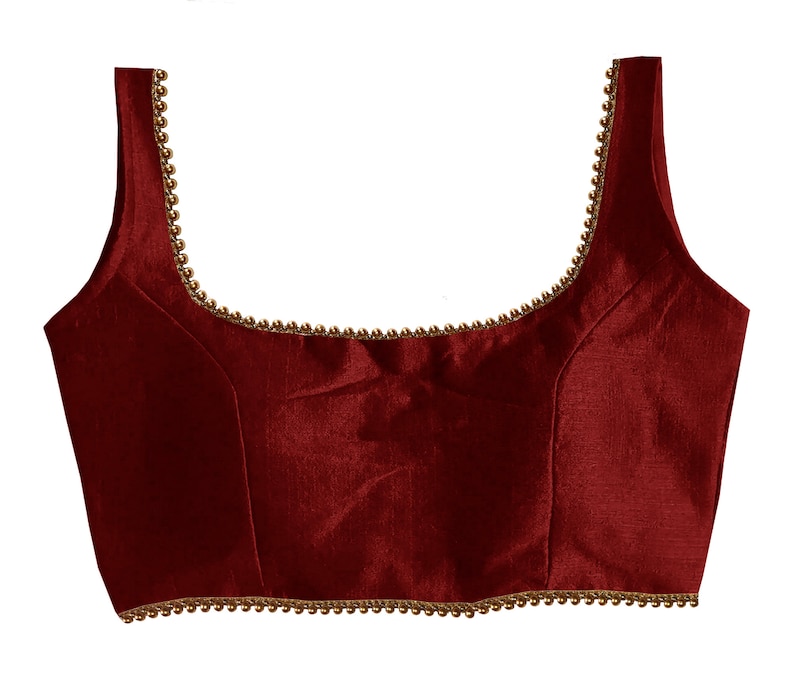 May include: A maroon sleeveless blouse with a gold beaded trim around the neckline.