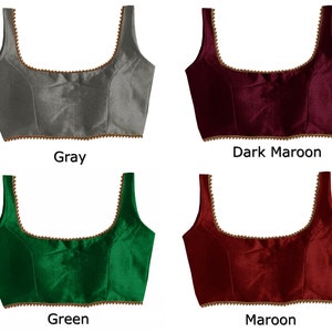 May include: Four different colored sleeveless blouses with a gold trim. The colors are gray, dark maroon, green, and maroon.