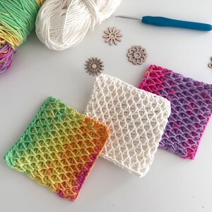 May include: Three crocheted squares in different colors and patterns. The squares are made with a textured stitch and are a light green, white, and purple.
