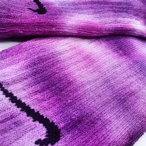 May include: Purple and white tie-dye socks with a black Nike swoosh logo.