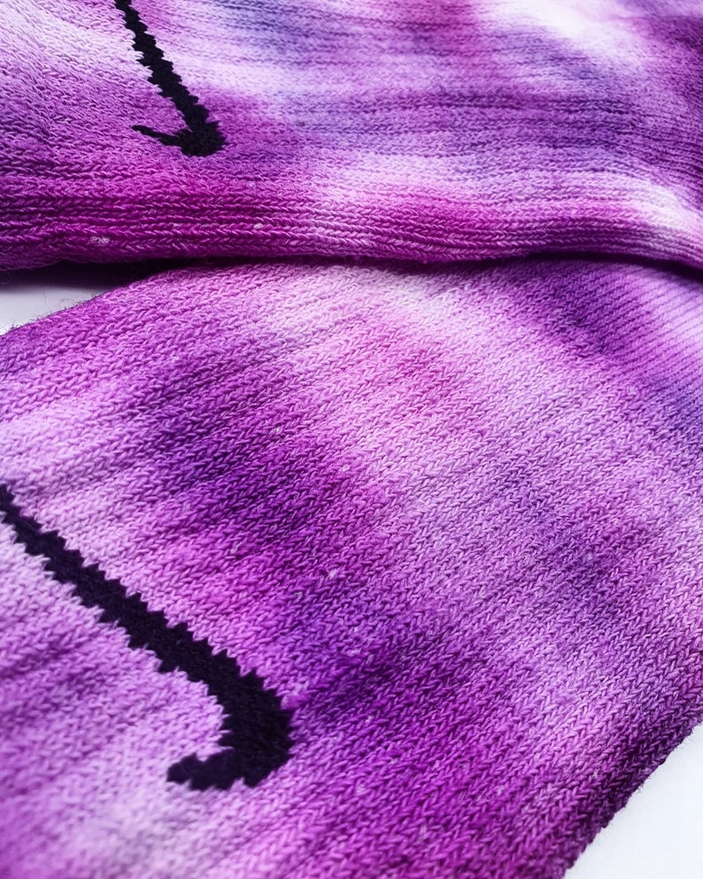 May include: Purple and white tie-dye socks with a black Nike swoosh logo.