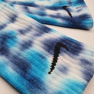 May include: A pair of blue and white tie-dye socks with a black Nike swoosh logo.