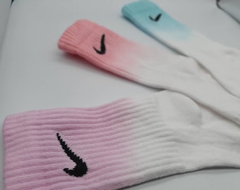 May include: Three pairs of ombre socks with a white to pink, white to blue, and white to light pink gradient. Each sock has a black Nike swoosh logo.