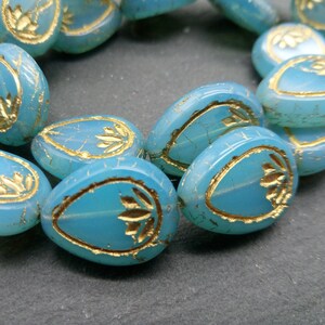 Puede incluir: Una hebra de cuentas de vidrio azul claro con acentos de pan de oro. Cada cuenta tiene forma de lágrima y presenta un diseño floral.