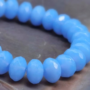 May include: A strand of light blue faceted glass beads. The beads are round and have a smooth, polished finish.