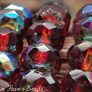 Könnte beinhalten: Nahaufnahme von irisierenden roten Glasperlen mit einer facettierten, geometrischen Form. Die Perlen haben eine dunkelrote Basis mit einem subtilen irisierenden Schimmer, der die Farbe im Licht verändert.