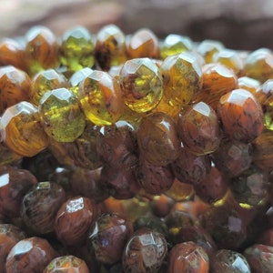 May include: A close-up of a strand of faceted glass beads. The beads are a mix of brown and green with a marbled effect.