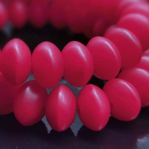 May include: A close-up of a strand of bright pink beads. The beads are round and smooth, and they are arranged in a circular pattern.