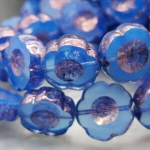 May include: A strand of blue glass beads with a flower shape and iridescent finish.