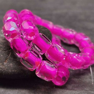 Könnte beinhalten: Eine Strähne aus rosa facettierten Glasperlen. Die Perlen sind irisierend und haben einen klaren Kern. Die Perlen sind auf einer durchsichtigen Gummikordel aufgefädelt.