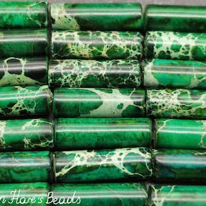May include: A collection of green and white marbled gemstone beads. The beads are cylindrical in shape and have a smooth, polished finish.