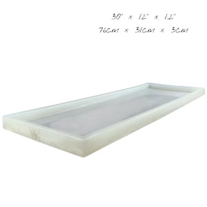 Puede incluir: Bandeja rectangular blanquecina con borde ligeramente elevado. Mide 76 cm de largo, 31 cm de ancho y 3 cm de profundidad. Superficie lisa, ideal para servir o exhibir.