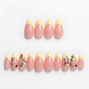 May include: A collection of almond-shaped false nails. Each nail has a yellow French tip and a pink base. Some nails are decorated with floral and ladybug designs. The nails are displayed on a white background.