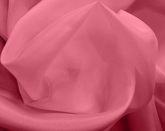 May include: A close-up of a soft, pink fabric with a smooth, silky texture. The fabric is draped and folded, creating a flowing, elegant look.