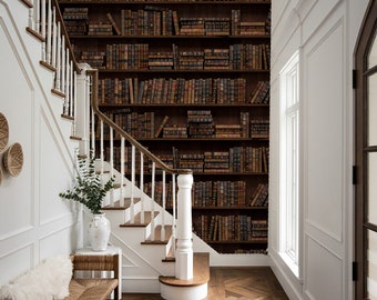 May include: A white staircase with wooden steps leads up to a landing with a white banister. The wall behind the staircase is covered in wallpaper that looks like a bookshelf filled with antique books. The floor is a dark brown herringbone pattern.