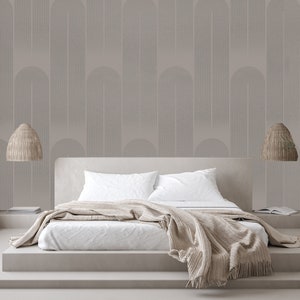 May include: A white bed with a beige blanket and two beige wicker pendant lights hanging above it. The wall behind the bed is covered in a light gray wallpaper with a geometric pattern.