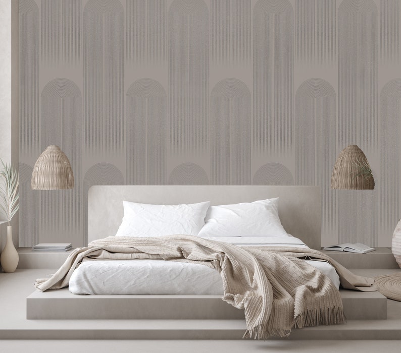 May include: A white bed with a beige blanket and two beige wicker pendant lights hanging above it. The wall behind the bed is covered in a light gray wallpaper with a geometric pattern.