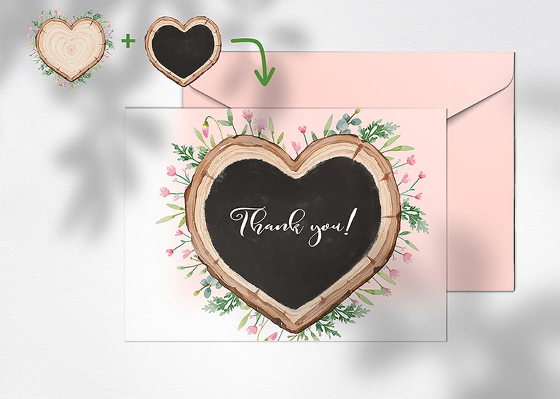 May include: A white card featuring a heart-shaped wood slice with a black chalkboard insert. The chalkboard displays the text "Thank you!" in elegant script. The wood slice is adorned with pink flowers and green foliage. The card is positioned beside a pink envelope.