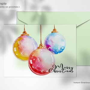 Puede incluir: Una ilustraci&oacute;n de acuarela de tres bolas de Navidad colgando de cuerdas. Las bolas est&aacute;n pintadas en tonos de rosa, azul, amarillo y blanco. El texto "Feliz Navidad" est&aacute; escrito en cursiva negra debajo de las bolas.