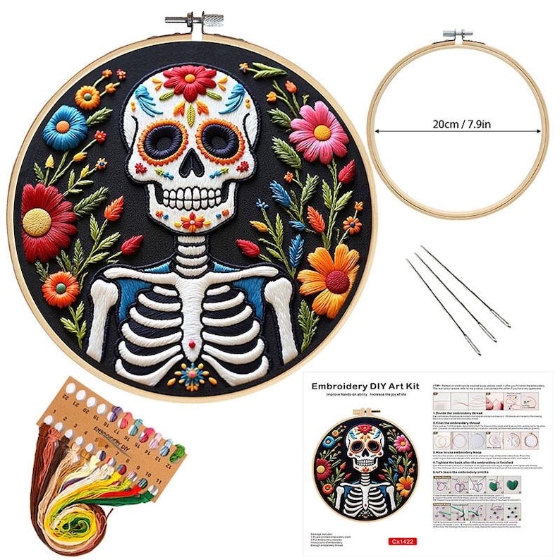 May include: Embroidery DIY art kit featuring a Day of the Dead skull design. The kit includes a 7.9-inch embroidery hoop, needles, thread, and instructions. The skull is surrounded by colorful flowers on a black background.