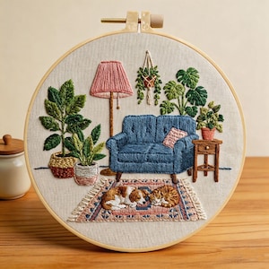 May include: Embroidered hoop art depicting a living room scene. A blue sofa, pink lamp, and potted plants are shown. A dog and cat are resting on a rug. The artwork is framed in a wooden hoop.