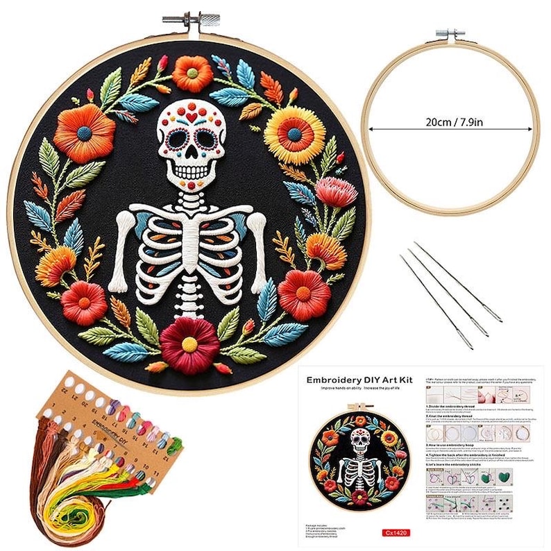 May include: Embroidery DIY art kit featuring a Day of the Dead skull and floral design. The kit includes a 7.9-inch (20 cm) embroidery hoop, needles, and colorful threads. The embroidered design is on a black background.