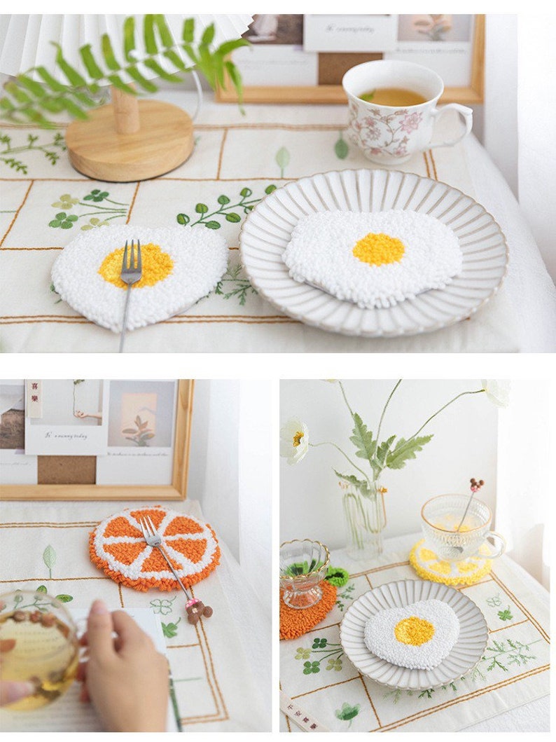 May include: Four white and yellow crocheted coasters with a variety of designs, including a fried egg, a slice of orange, and a heart. The coasters are on a white tablecloth with a floral pattern.