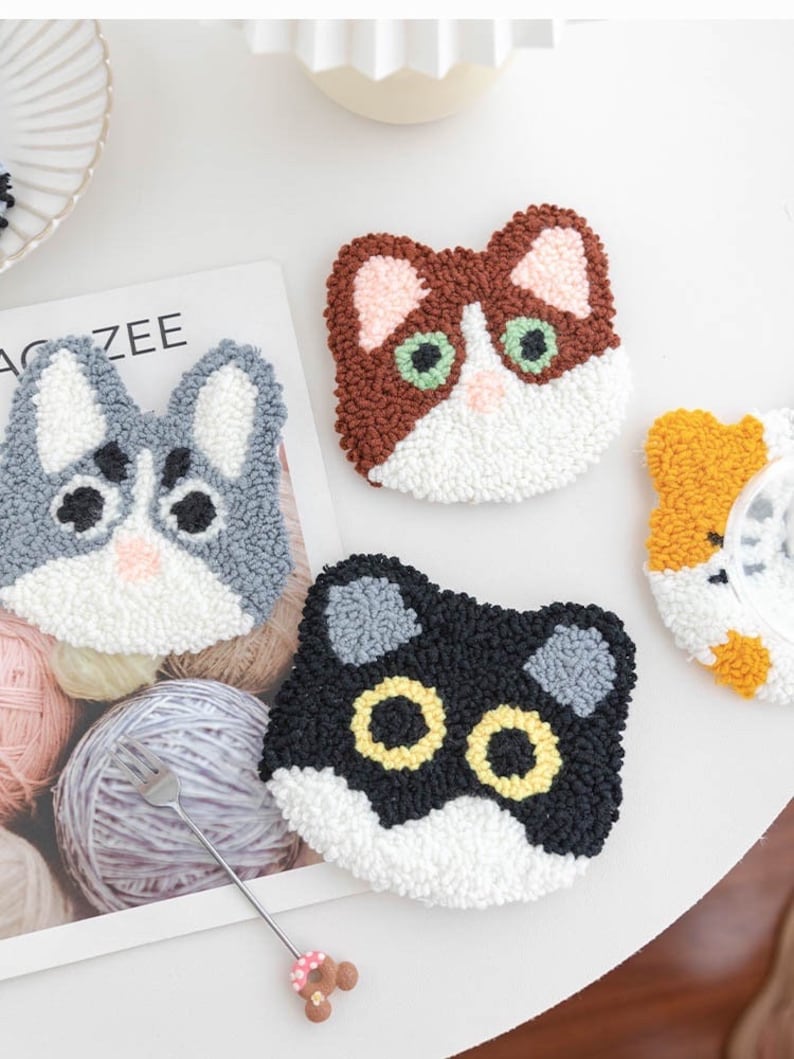 May include: Three colorful cat-shaped punch needle kits. The cats are brown and white, gray and white, and black and white. Each kit includes a pre-punched canvas, yarn, and a needle.