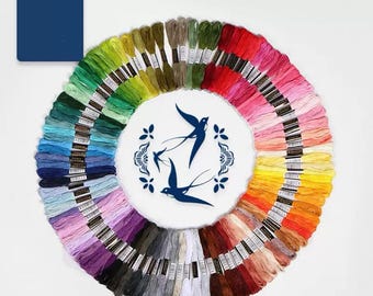 Peut inclure: Présentation circulaire de 100 couleurs de fil à broder, disposées en arc-en-ciel. Le fil est disposé autour d'un cercle blanc avec des illustrations d'oiseaux bleus. Un carré bleu avec le texte "100 couleurs" est en haut à gauche.