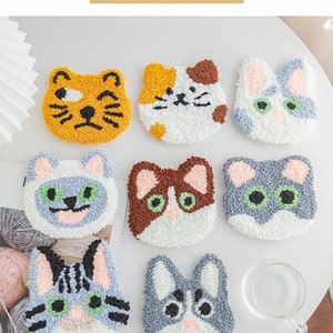 May include: Nine colorful felt cat-shaped DIY punch needle kits. Each kit features a different cat design with various colors and patterns. The kits are perfect for crafting and creating unique home decor.