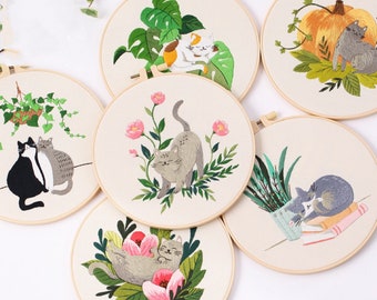 May include: Six embroidery hoops with different cat designs. The designs include cats sleeping, cuddling, and playing in a variety of settings, including a potted plant, a pumpkin, and flowers.
