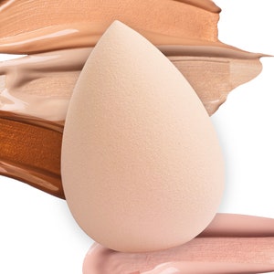 K&ouml;nnte beinhalten: Ein hellbeiger Make-up-Schwamm in Tropfenform, der auf drei Farbmuster von Foundation liegt. Die Farbmuster sind in den Farben hellbeige, mittelbeige und dunkelbraun.