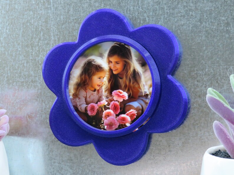 May include: A blue flower-shaped photo frame with a picture of two girls smiling and holding pink flowers.